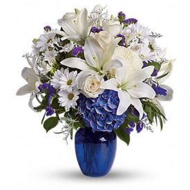 beautiful bouquet pairs pure white flowers with deep blue blooms in a gorgeous blue glass vase